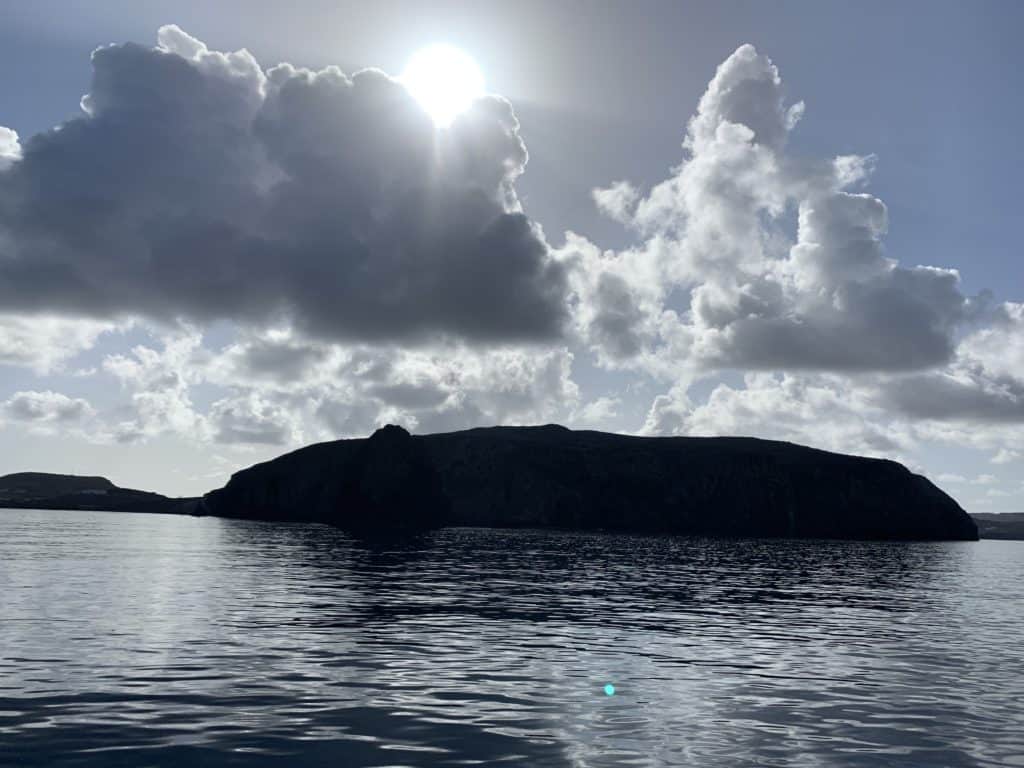 island with sun behind clouds